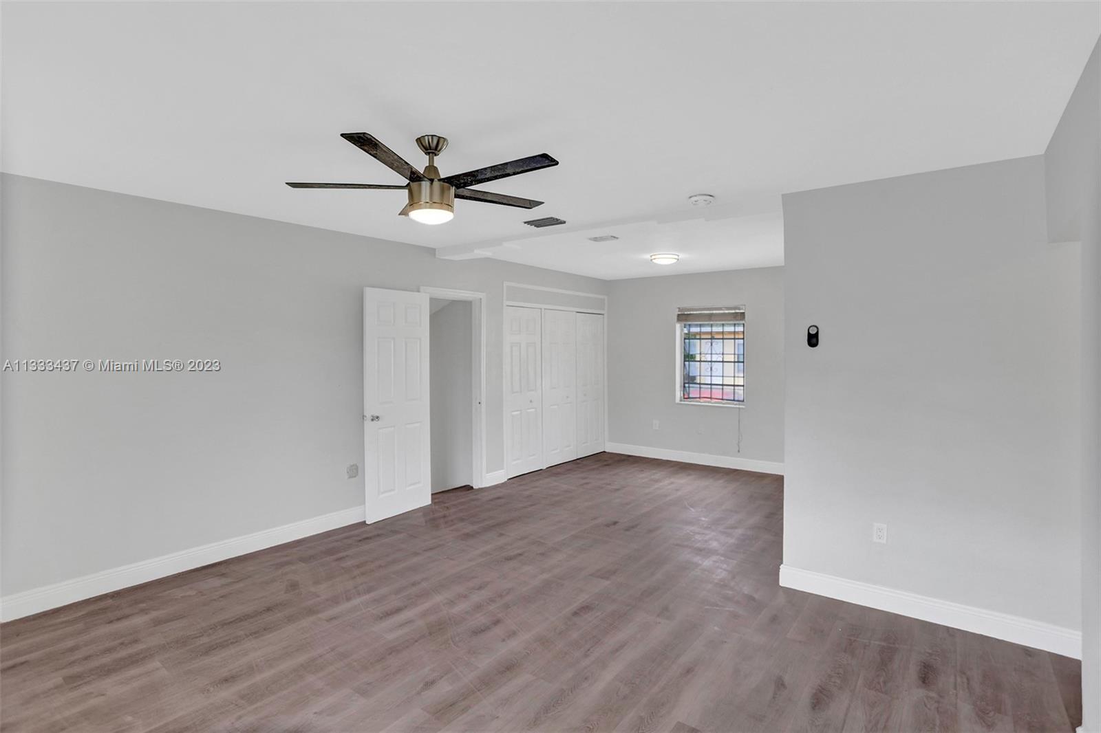 1101 Northwest 147th Street Miami, FL 33168 - Photo 7 of 45 an empty room with wooden floor ceiling fan and windows