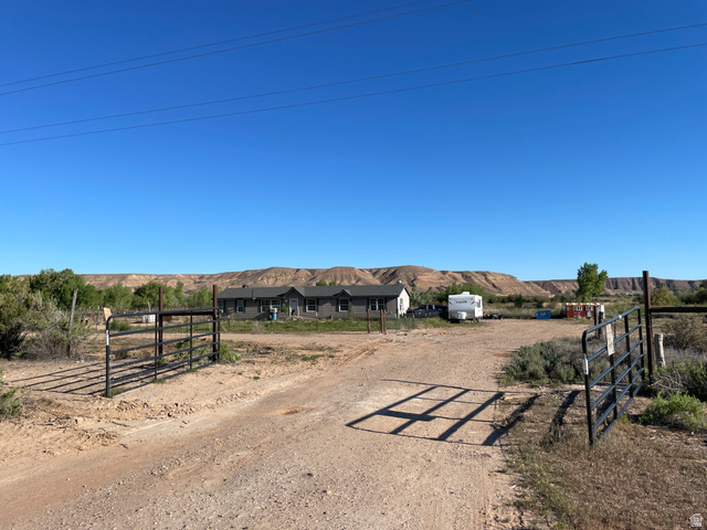 240 Horseshoe Bend Road Vernal, UT 84078 - Photo 3 of 41 Gated entry opens to a expansive gravel lot with a backdrop of natural rock formations and distant greenery