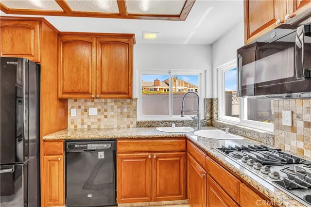 a kitchen with stainless steel appliances granite countertop wooden cabinets a stove and a sink