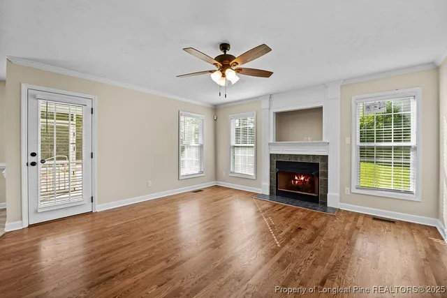 a view of an empty room with wooden floor fireplace and a window