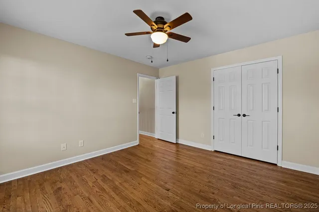 a view of an empty room with window and wooden floor