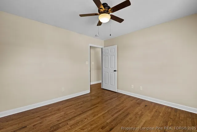 an empty room with wooden floor and a ceiling fan