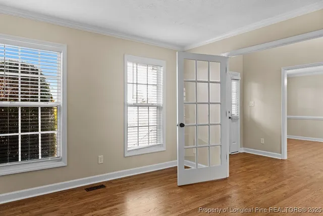an empty room with wooden floor and windows