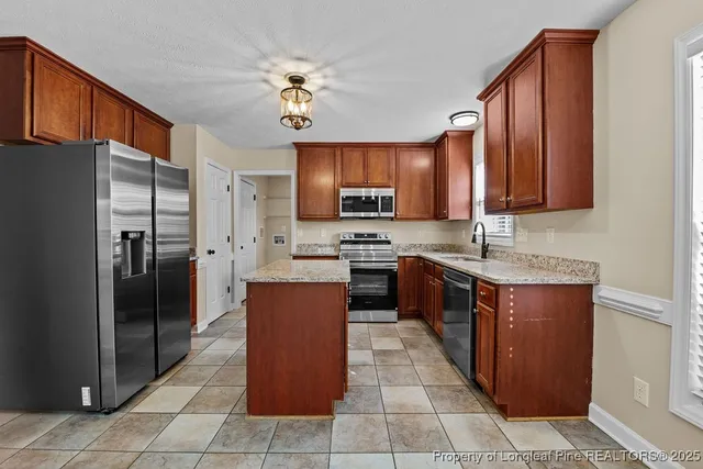 a kitchen with stainless steel appliances granite countertop a refrigerator a sink a stove a microwave and island