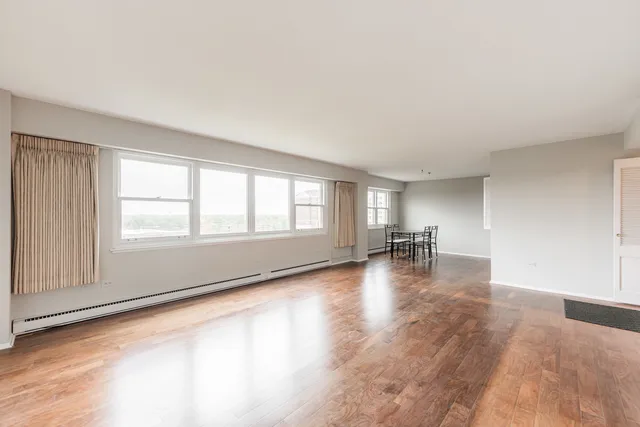 a view of empty room with wooden floor and floor to ceiling window
