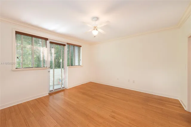 a view of empty room with wooden floor and fan