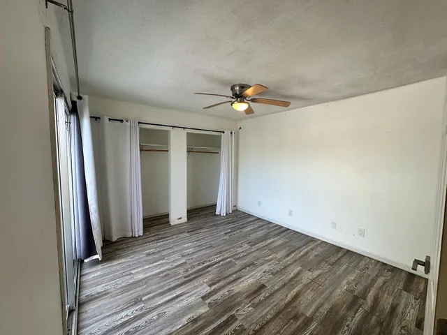 en empty room with wooden floor and ceiling fan