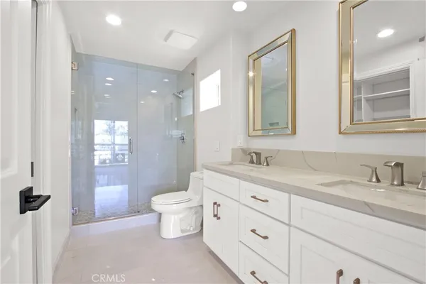 a spacious bathroom with a granite countertop sink toilet a large mirror a shower and a