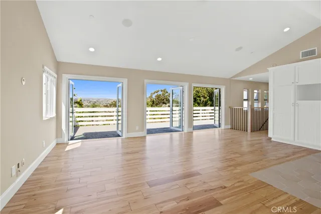 a view of an empty room with a window and wooden floor