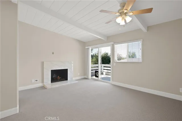 an empty room with windows fireplace and fan