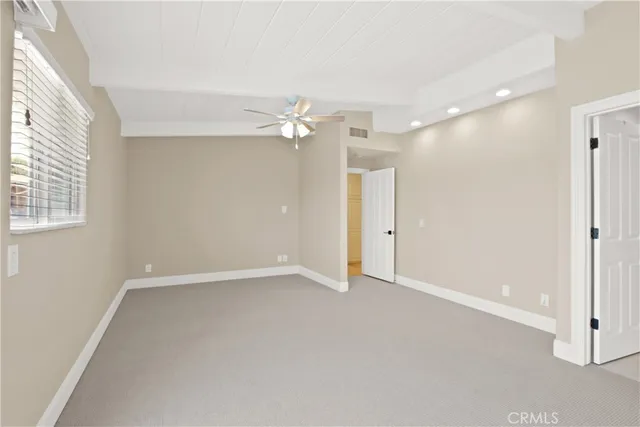 an empty room with chandelier fan and windows