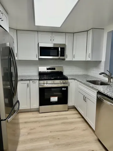 a kitchen with cabinets stainless steel appliances and a counter space