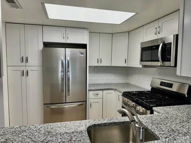 a kitchen with stainless steel appliances granite countertop a stove a refrigerator and a microwave