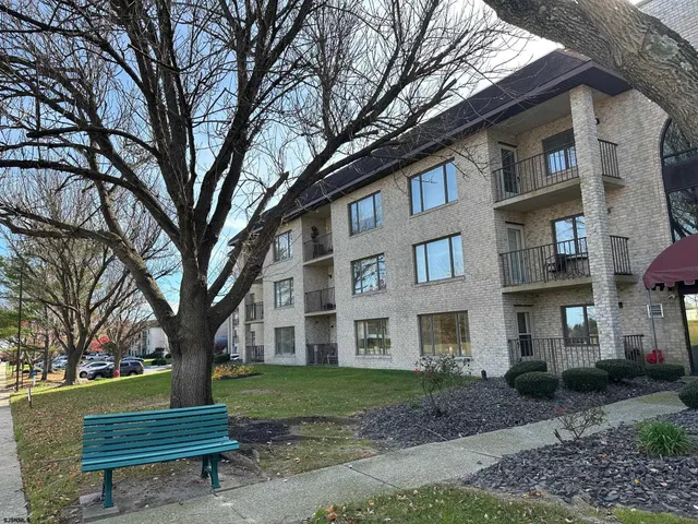 a view of a brick house with a bench next to a yard