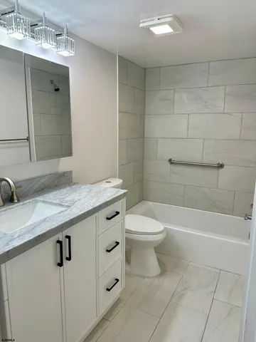 a bathroom with a granite countertop sink a toilet and bathtub