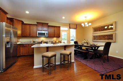 2430 Pecan Ridge Way Apex, NC 27502 - Photo 10 of 23 Island with breakfast bar, granite countertops, tall cabinets, stainless appliances. Not actual home - photo is of model home. Actual home will have similar features.