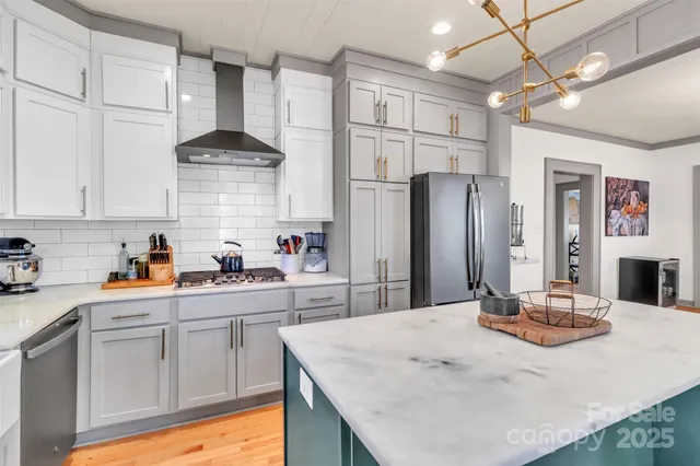 a kitchen with stainless steel appliances kitchen island granite countertop a refrigerator a sink dishwasher and white cabinets with wooden floor