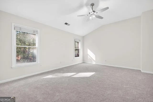 an empty room with windows and ceiling fan