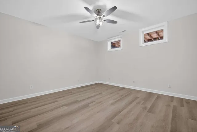 an empty room with a window and a ceiling fan