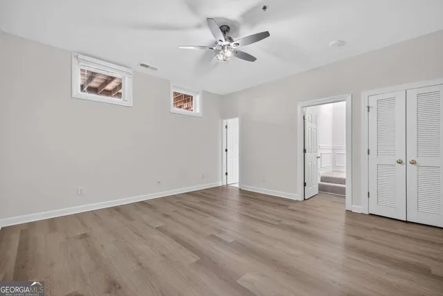 an empty room with wooden floor and ceiling fan