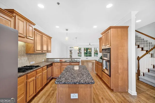 a large kitchen with stainless steel appliances granite countertop a stove a sink and a refrigerator