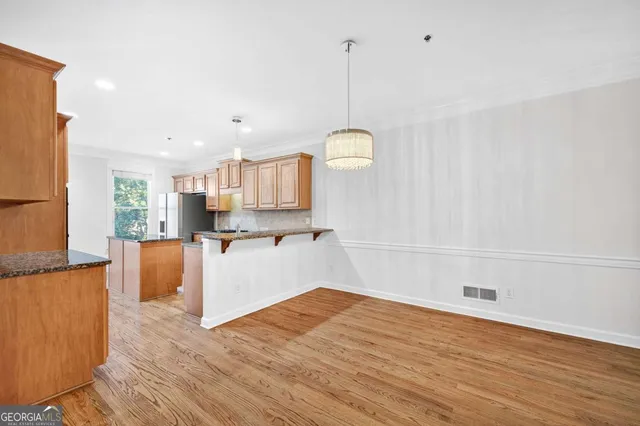 a open kitchen with kitchen island a stove a refrigerator a sink and a wooden floor