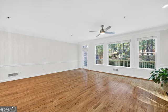 a view of an empty room with a window and wooden floor