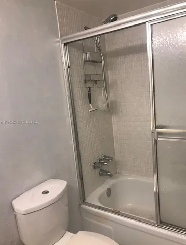 a bathroom with a granite countertop bathtub shower and toilet