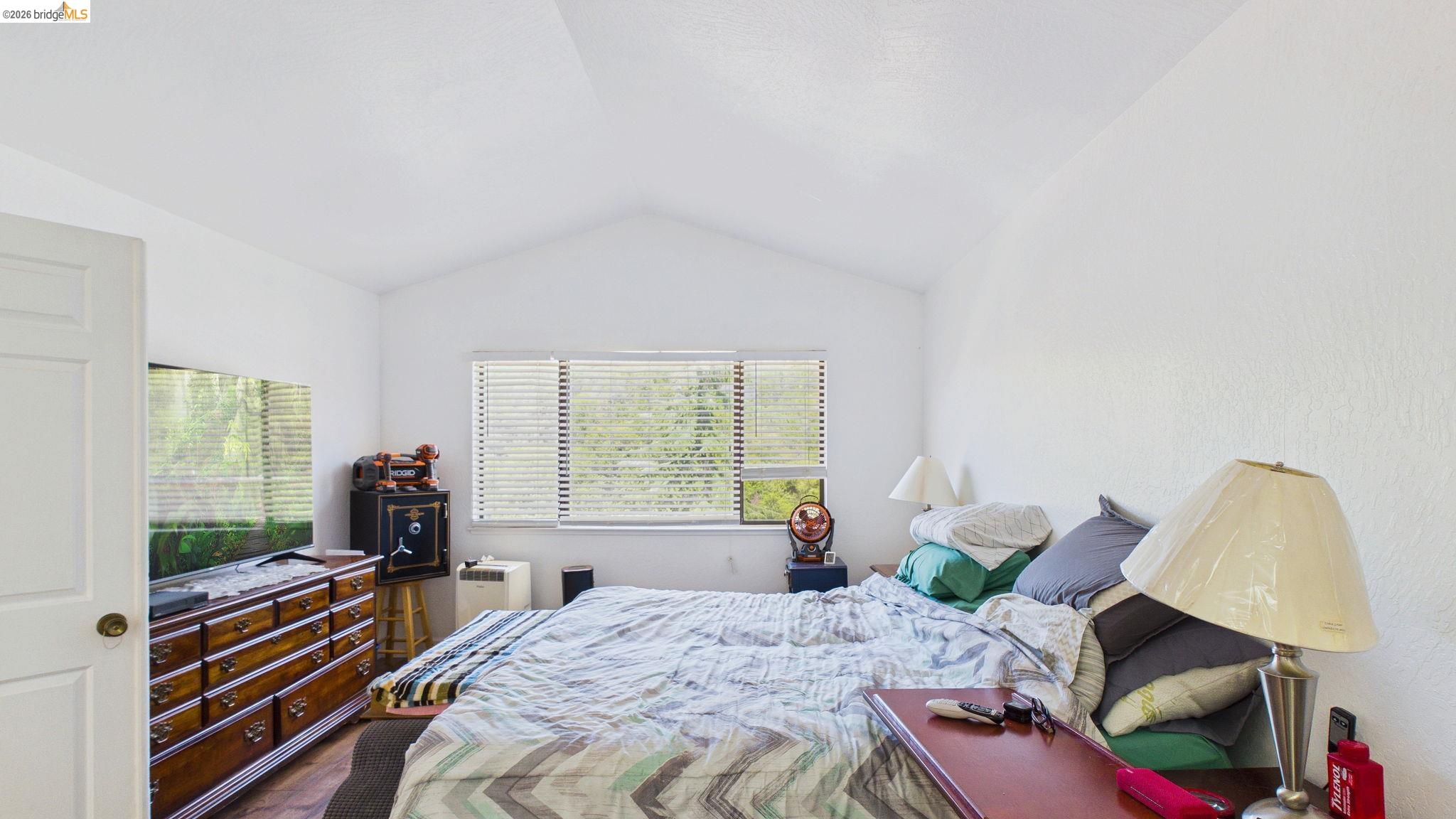 11858 Campo Seco Road Sonora, CA 95370 - Photo 28 of 45 Vaulted ceiling with textured finish, white painted walls, window with horizontal blinds, and wood-finish flooring