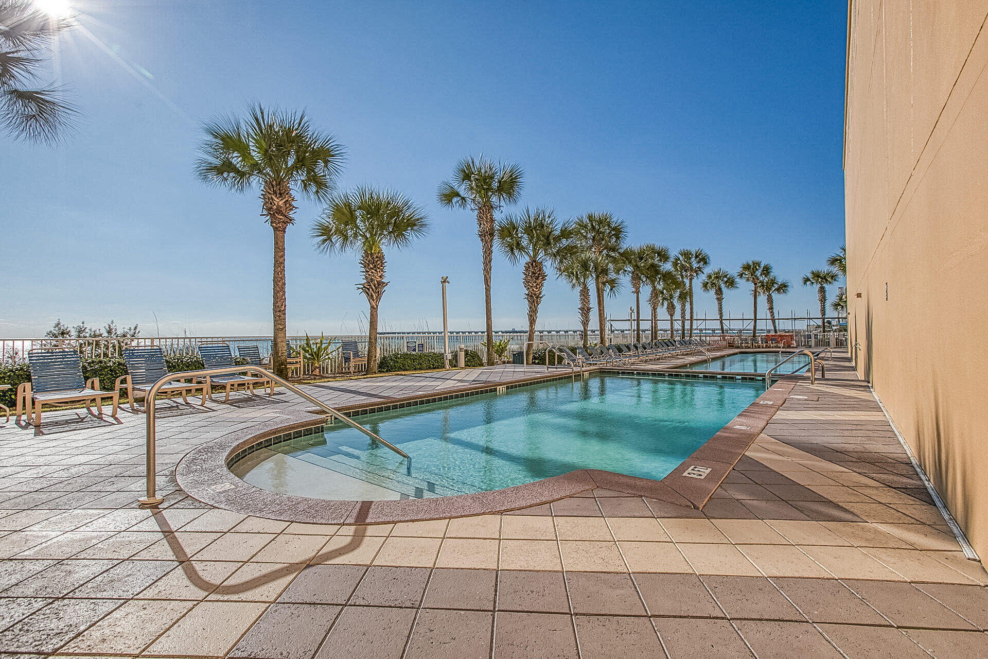 12011 Front Beach Road, Unit 701 Panama City Beach, FL 32407 - Photo 40 of 42 a view of a swimming pool with a lounge chair and palm trees