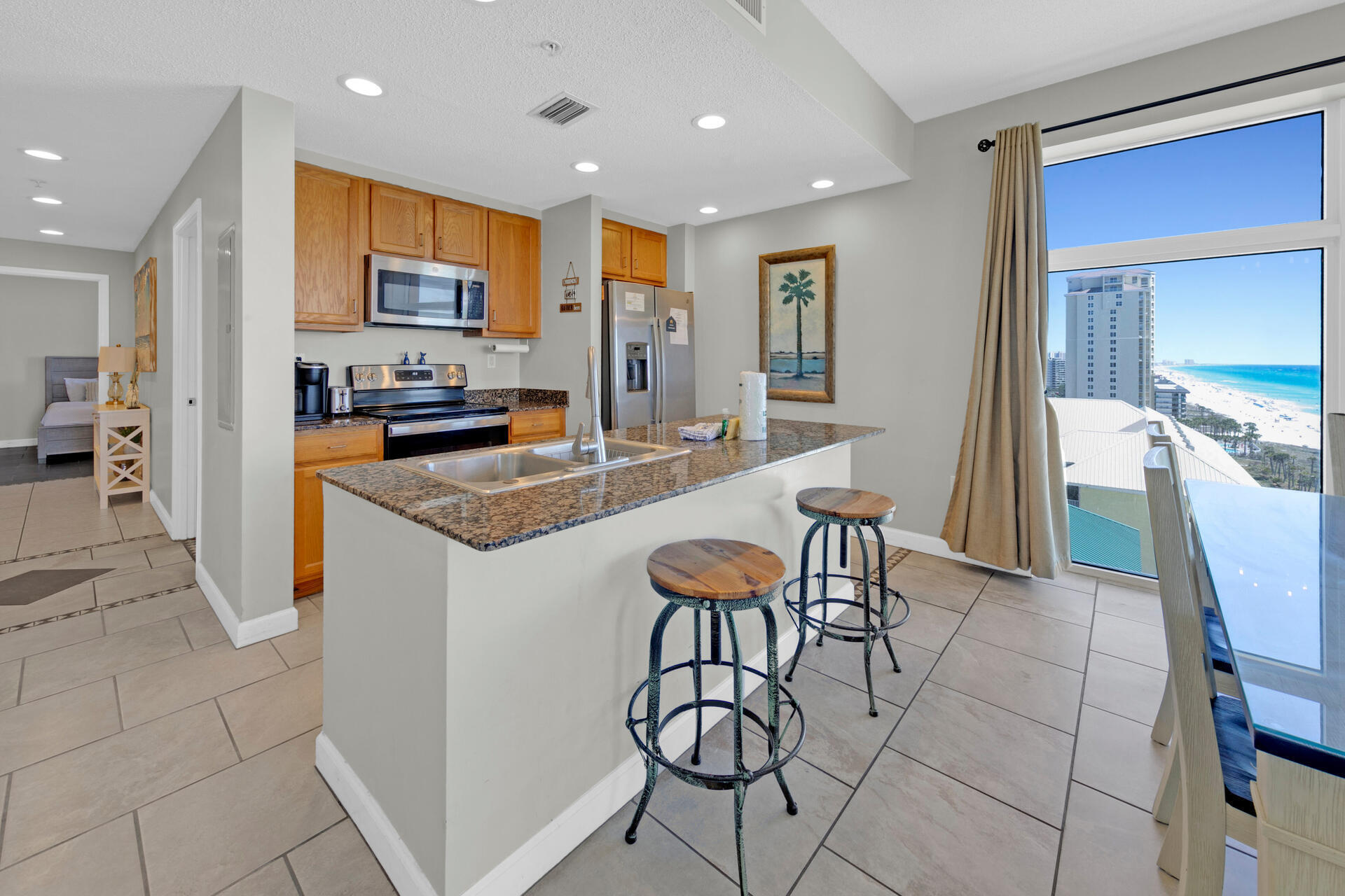 12011 Front Beach Road, Unit 701 Panama City Beach, FL 32407 - Photo 8 of 42 a kitchen with stainless steel appliances granite countertop a table and chairs in it