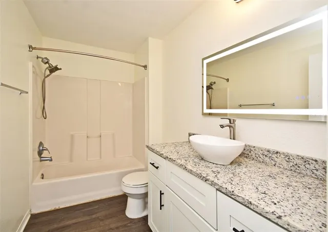 a bathroom with a granite countertop sink a toilet and shower