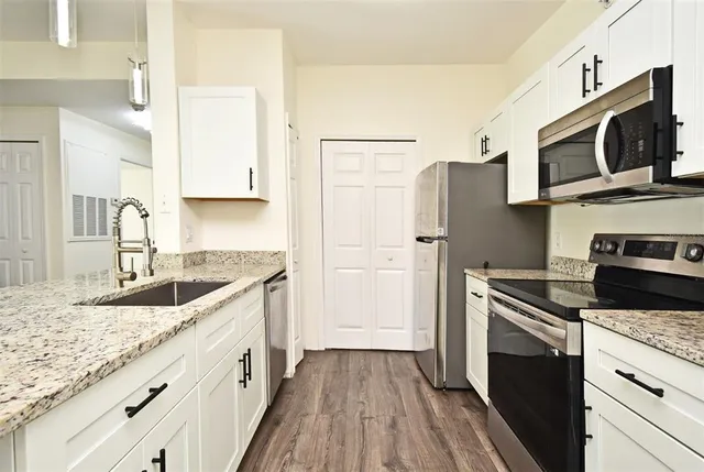 a kitchen with granite countertop a sink stove and refrigerator