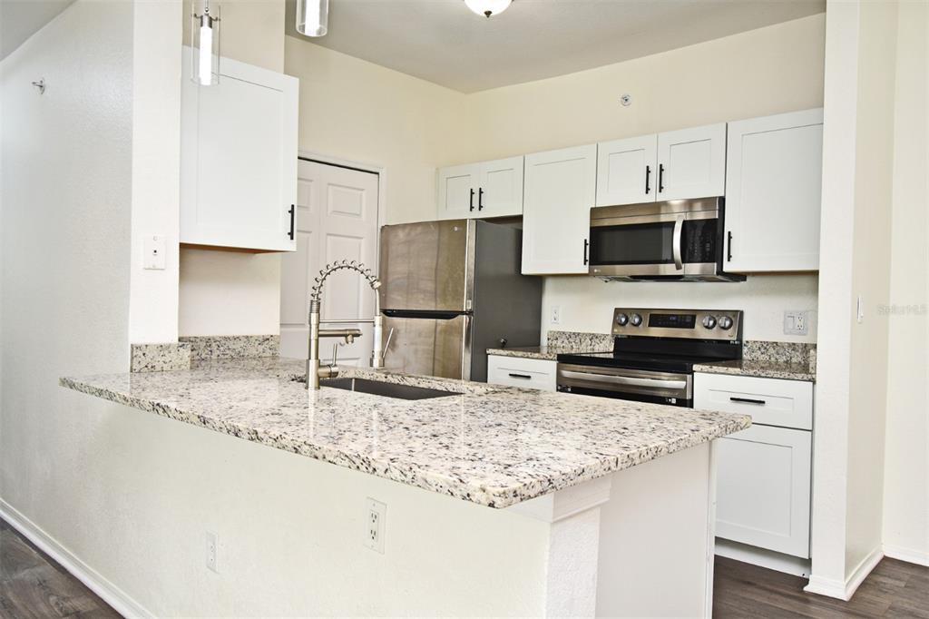 5467 Vineland Road, Unit 6308 Orlando, FL 32811 - Photo 23 of 36 a kitchen with stainless steel appliances granite countertop a sink refrigerator and microwave