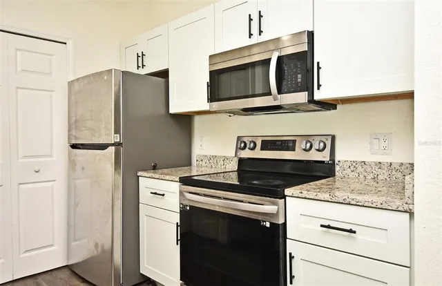 a kitchen with stainless steel appliances granite countertop a stove microwave and refrigerator