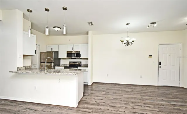 a view of a kitchen with kitchen island stainless steel appliances a sink and wooden floor