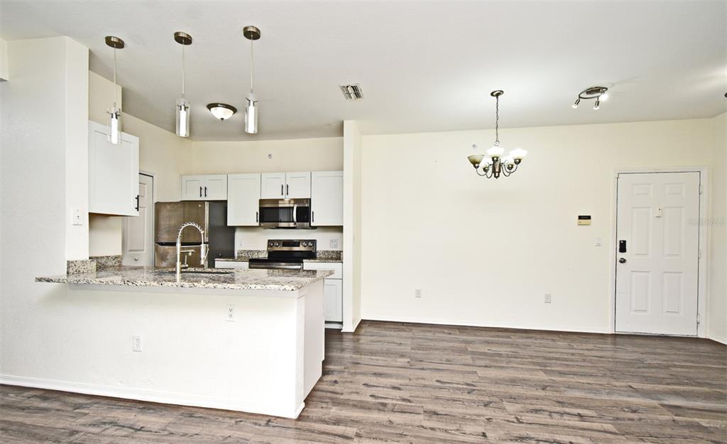 5467 Vineland Road, Unit 6308 Orlando, FL 32811 - Photo 25 of 36 a view of a kitchen with kitchen island stainless steel appliances a sink and wooden floor