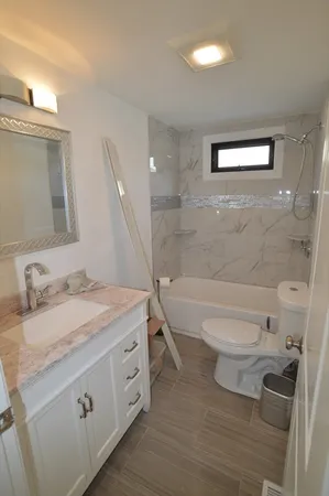 a bathroom with a granite countertop toilet a sink and a bathtub