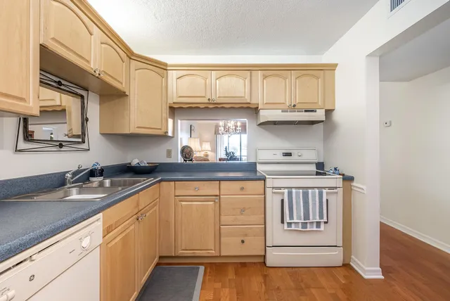 a kitchen with stainless steel appliances granite countertop a sink and cabinets with wooden floor