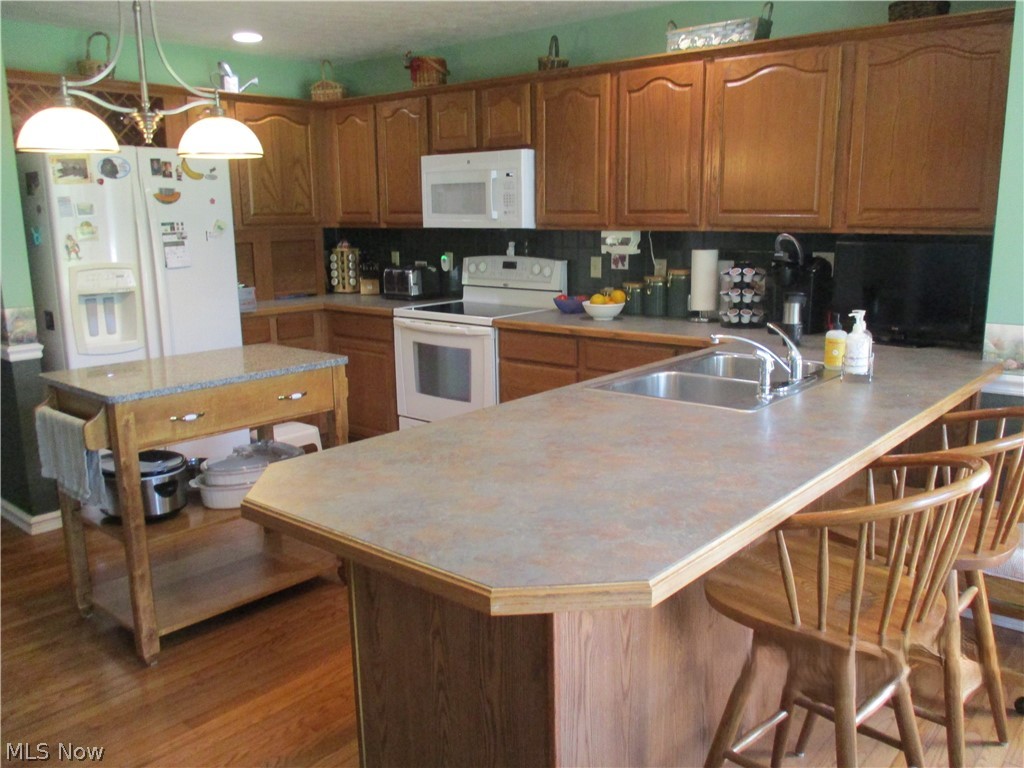 7540 Kennard Road Seville, OH 44273 - Photo 9 of 37 Kitchen featuring light hardwood / wood-style floors, white appliances, kitchen peninsula, pendant lighting, and tasteful backsplash
