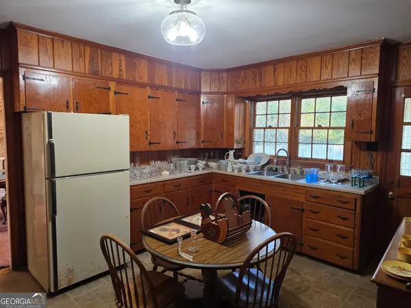 a kitchen with stainless steel appliances granite countertop a refrigerator a sink a stove a dining table and chairs with wooden floor