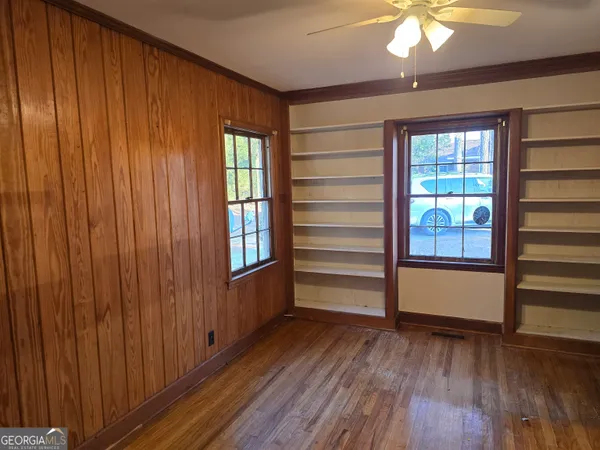 a view of empty room with wooden floor and fan