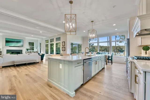 a kitchen with stainless steel appliances granite countertop a stove a sink and white cabinets with wooden floor