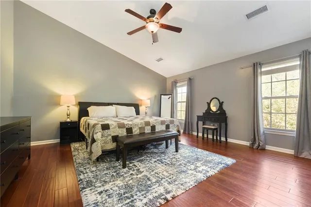 a bed sitting in a spacious bedroom next to a window with a flat screen tv