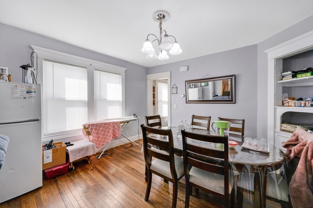 100-102 Wait Street Springfield, MA 01104 - Photo 5 of 35 a dining room with wooden floor a chandelier a wooden table and chairs