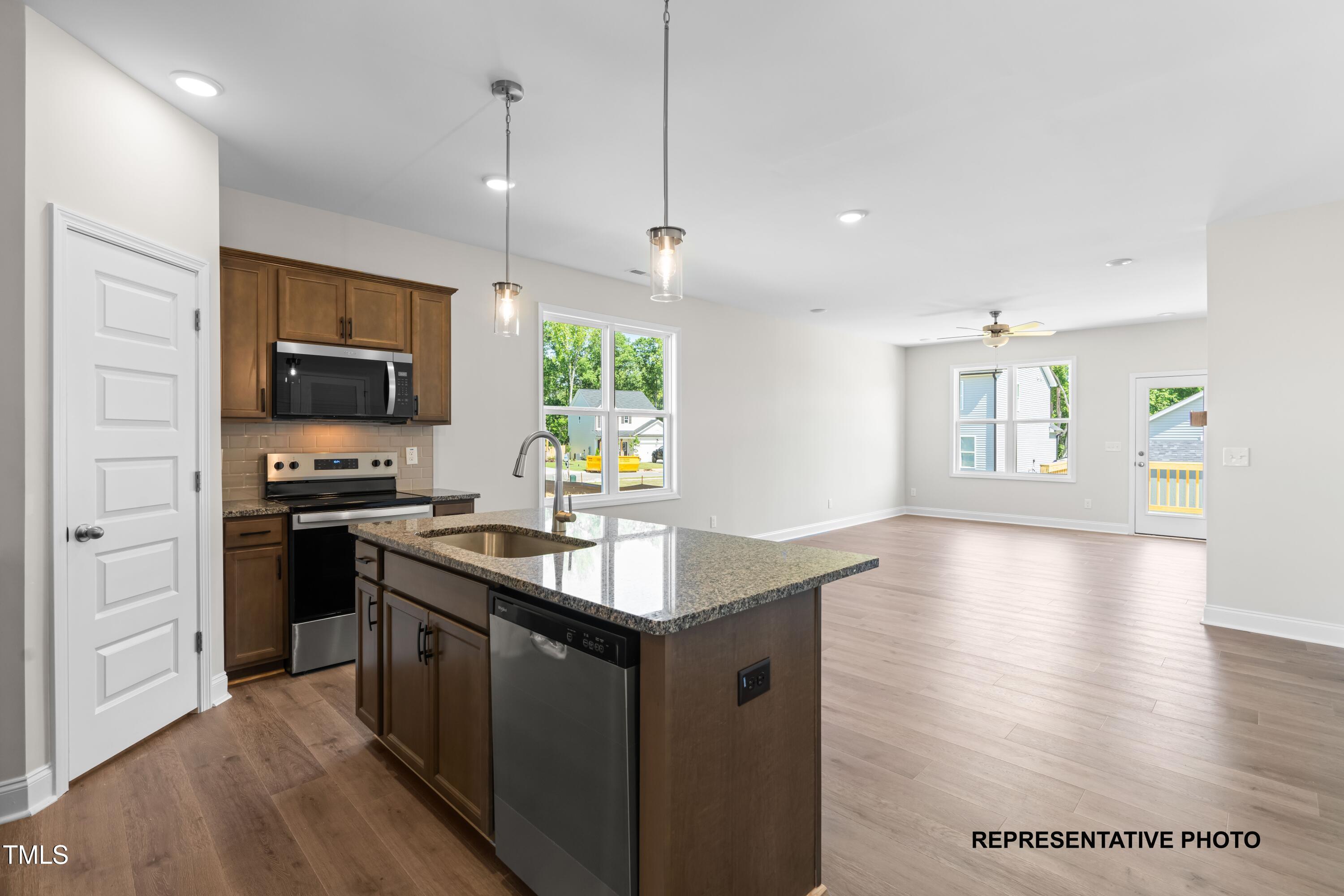 286 Bluejay Street Clayton, NC 27520 - Photo 2 of 12 a kitchen with granite countertop a stove top oven a sink dishwasher a dining table and chairs with wooden floor