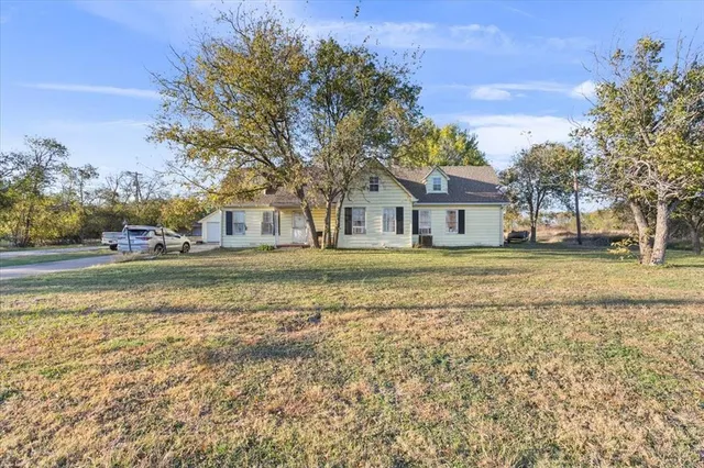 a view of a car park in front of a brick house with a large tree