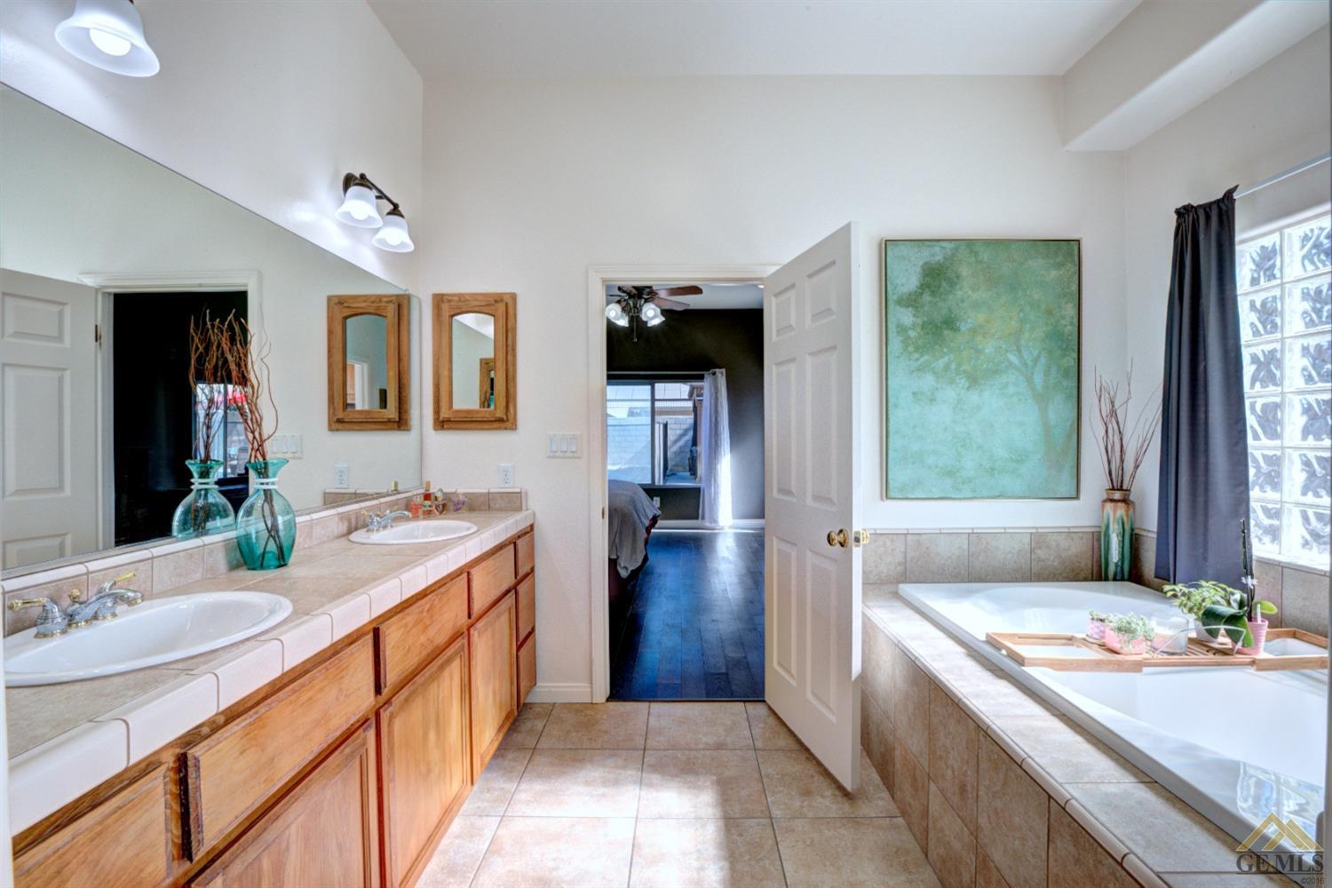Undisclosed Address Shafter, CA 93263 - Photo 11 of 21 a bathroom with a granite countertop sink a mirror a bathtub and next to a window