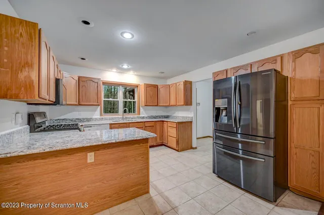 a kitchen with stainless steel appliances granite countertop a refrigerator a sink and a stove