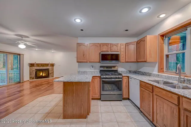 a large kitchen with stainless steel appliances granite countertop a stove top oven a sink dishwasher and white cabinets with wooden floor